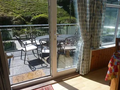 a patio with a table and chairs on a balcony at Tides Reach - Trebarwith Strand - North Cornwall - Sleeps 4 - 6 in Treknow