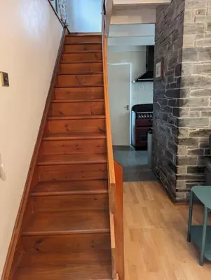 a wooden staircase in a room with a brick wall at Tides Reach - Trebarwith Strand - North Cornwall - Sleeps 4 - 6 in Treknow