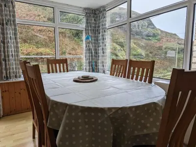 a dining room with a table and a large window at Tides Reach - Trebarwith Strand - North Cornwall - Sleeps 4 - 6 in Treknow