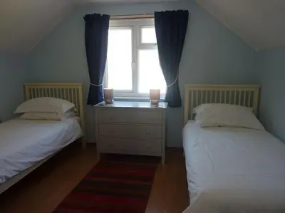a bedroom with two beds and a window with two candles at Tides Reach - Trebarwith Strand - North Cornwall - Sleeps 4 - 6 in Treknow