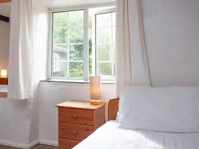 a bedroom with a bed and a candle on a night stand at Linhay in Looe