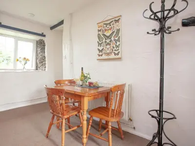 a dining room with a wooden table and chairs at Linhay in Looe