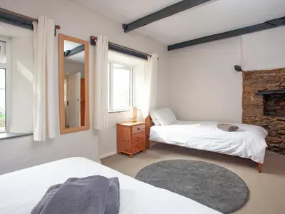 a bedroom with two beds and a mirror at Linhay in Looe