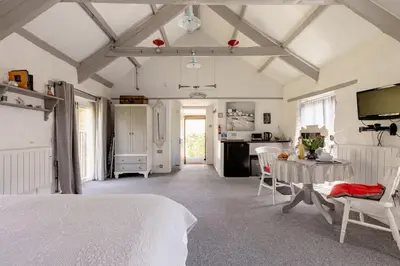 a bedroom with a white bed and a table and chairs at Chypons Farm Bed & Breakfast in Penzance