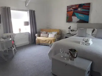 a bedroom with a bed and a chair and a window at Chypons Farm Bed & Breakfast in Penzance