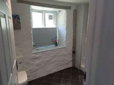 a bathroom with a window and a sink and a toilet at Chypons Farm Bed & Breakfast in Penzance