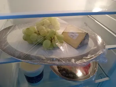 a piece of cheese and grapes on a plate in a refrigerator at Chypons Farm Bed & Breakfast in Penzance