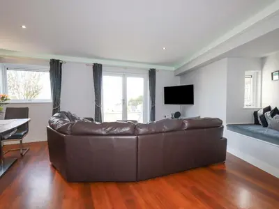 a living room with a leather couch and a television at Apartment 2 in Newquay