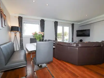 a living room with a leather couch and a table at Apartment 2 in Newquay