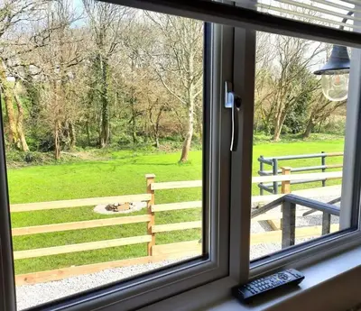 a window with a view of a park with a fence at Beautiful Cabin near Padstow in Padstow