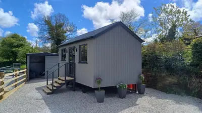 a small white shed with stairs and potted plants at Beautiful Cabin near Padstow in Padstow