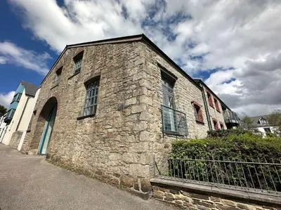an old stone building with a fence in front of it at Polmear Apartments, Charlestown in Charlestown