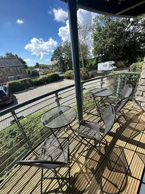 three chairs and a table on a deck at Polmear Apartments, Charlestown in Charlestown