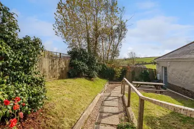 a garden with a wooden fence and a bench at Sunlight Cottage in Truro
