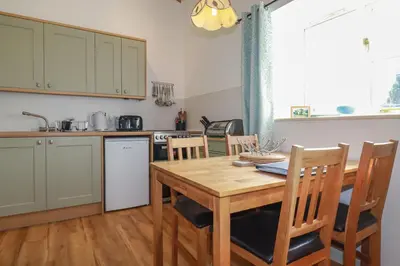 a kitchen with a wooden table and chairs and a kitchen with a table at Sunlight Cottage in Truro