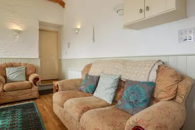 a living room with a couch and two chairs at Sunlight Cottage in Truro