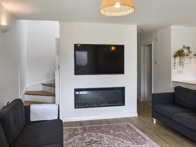 a living room with a fireplace and a tv on a wall at Halcyons Rest in Saint Tudy