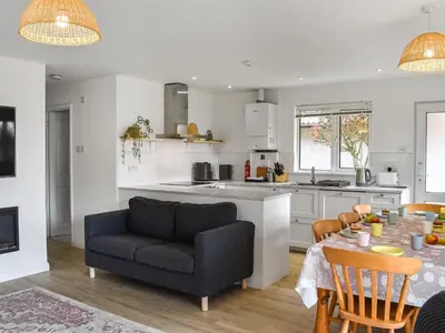 a kitchen and living room with a table and a couch at Halcyons Rest in Saint Tudy