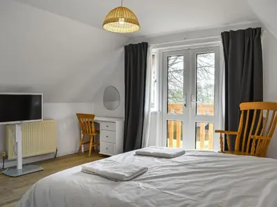 a bedroom with a bed and a tv and a window at Halcyons Rest in Saint Tudy