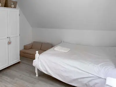 a bedroom with a white bed and a couch at Halcyons Rest in Saint Tudy