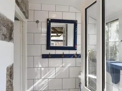 a bathroom with white tiled walls and a mirror at Barn Cottage - Uk47089 in Davidstow