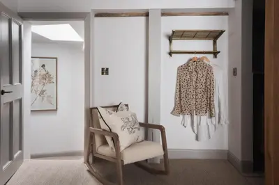 a living room with a rocking chair and a coat at Kittiwake Cottage - Charming harbour-side cottage, luxury interiors in Port Isaac