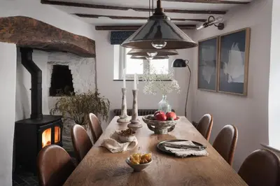 a dining room with a wooden table and a fireplace at Kittiwake Cottage - Charming harbour-side cottage, luxury interiors in Port Isaac
