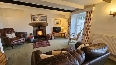 a living room with a leather couch and a fireplace at Barton Bothy in Porthscatho