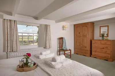 a bedroom with two beds and a window and a dresser at Barton Bothy in Porthscatho