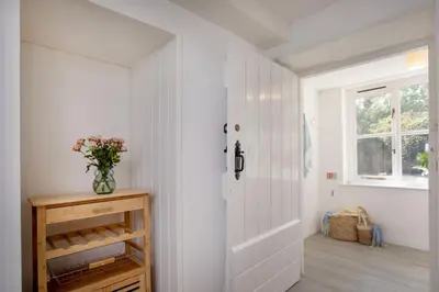 a hallway with a white door and a vase of flowers at Barton Bothy in Porthscatho
