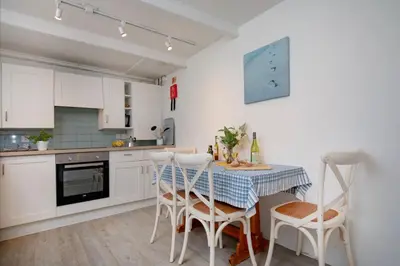 a kitchen with white cabinets and a table and chairs at Barton Bothy in Porthscatho