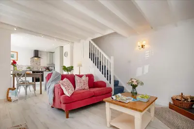 a living room with a red couch and a table at Lavender Cottage in Porthscatho