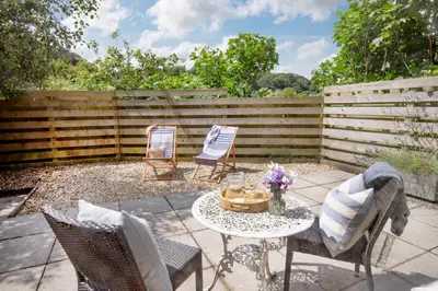 a patio with two chairs and a table and a fence at Lavender Cottage in Porthscatho