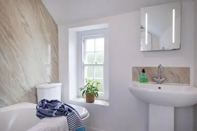 a white bathroom with a sink and a tub at Lavender Cottage in Porthscatho