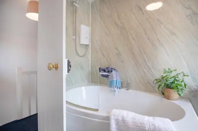 a bathroom with a tub with a cat on the wall at Lavender Cottage in Porthscatho