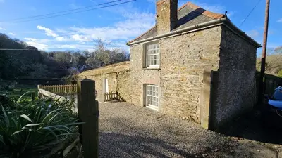 an old stone house with a fence in front of it at Lavender Cottage in Porthscatho