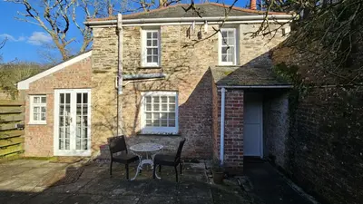a brick house with a table and chairs in front of it at Lavender Cottage in Porthscatho