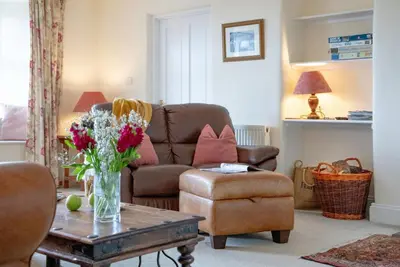 a living room with a couch and a vase of flowers on a table at Meadow House in Porthscatho