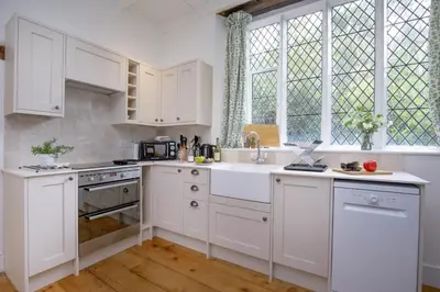 a white kitchen with white cabinets and windows at Place Lodge in Porthscatho