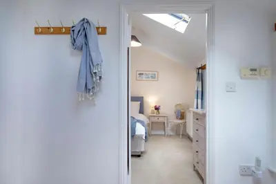 a hallway with a door to a bedroom with a bed at Place Lodge in Porthscatho