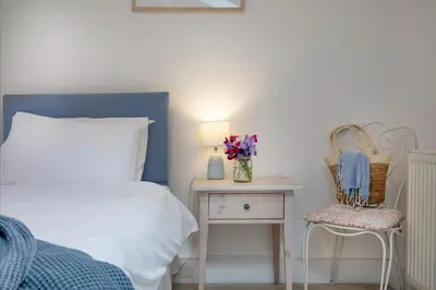 a bedroom with a bed and a table with a vase of flowers at Place Lodge in Porthscatho