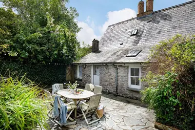 a table and chairs in front of a cottage at Place Lodge in Porthscatho