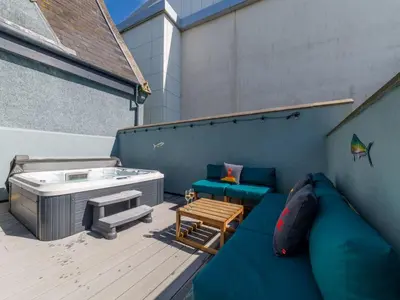 a patio with a hot tub and a couch and a table at Holiday Home Tolcarne by Interhome in Newquay
