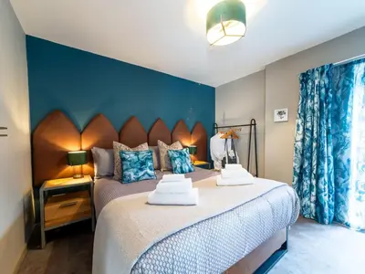 a bedroom with a large bed and a blue wall at Holiday Home Tolcarne by Interhome in Newquay