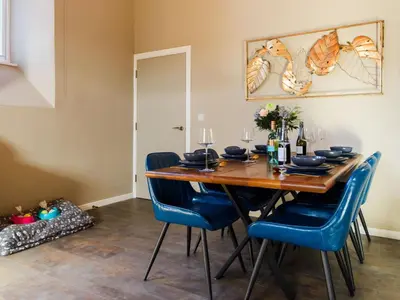 a dining room with a wooden table and blue chairs at Holiday Home Seaside House by Interhome in Newquay