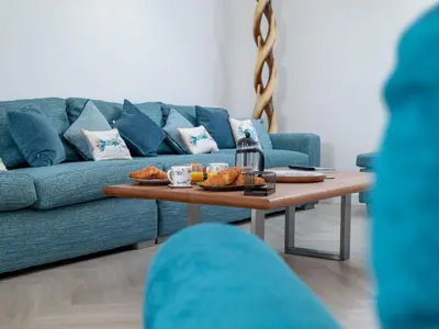 a living room with a blue couch and a coffee table at Holiday Home Sun Trap by Interhome in Newquay