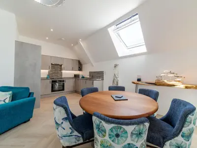 a kitchen and living room with a wooden table and chairs at Holiday Home Sun Trap by Interhome in Newquay