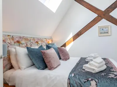 a bedroom with a white bed with blue and pink pillows at Holiday Home Sun Trap by Interhome in Newquay