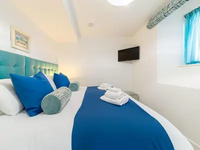a bedroom with a blue and white bed with blue pillows at Holiday Home Sun Trap by Interhome in Newquay