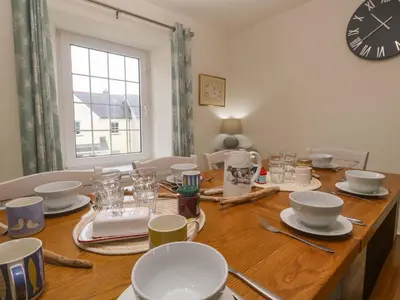 a dining room table with a clock on the wall at Fair View in Truro